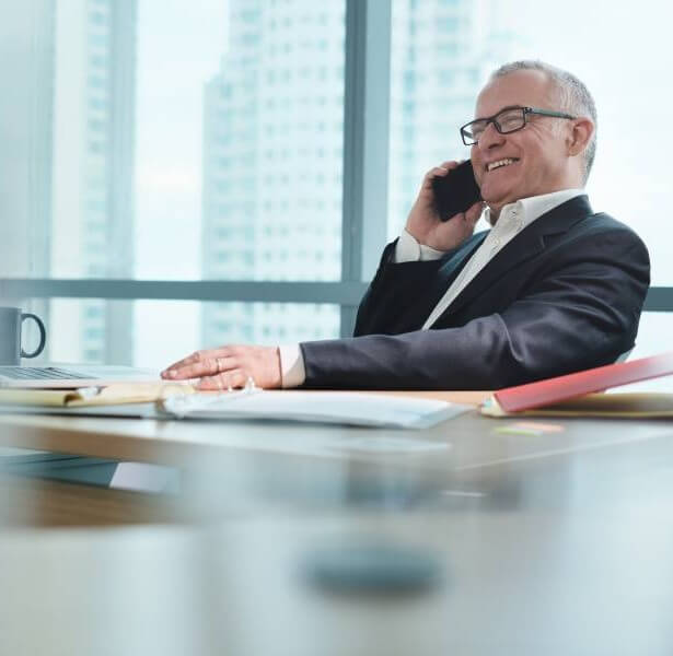 Male Entrepreneur Mature male entrepreneur sitting at a desk talking on a mobile phone with a smile
