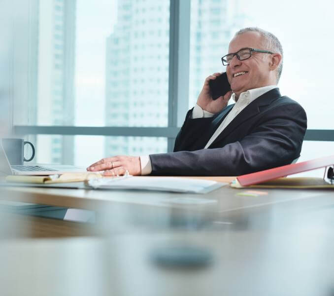 Male-Entrepreneur Businessman sitting at a desk while on a mobile phone