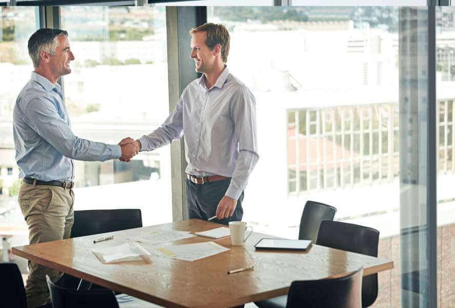 Onboarding-Deal Two men shaking hands in an office